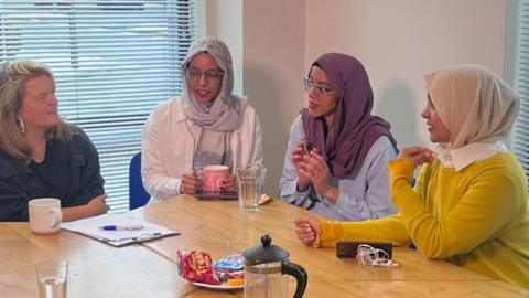 Five women gathered around a table