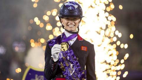 Britain's Charlotte Fry smiles and holds up her freestyle dressage gold medal