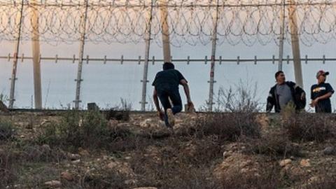 Migrants run after crossing the Mexico-US border fence in Tijuana, Mexico