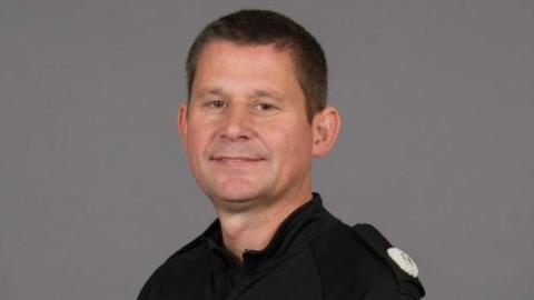 Man with short dark hair wearing a police uniform