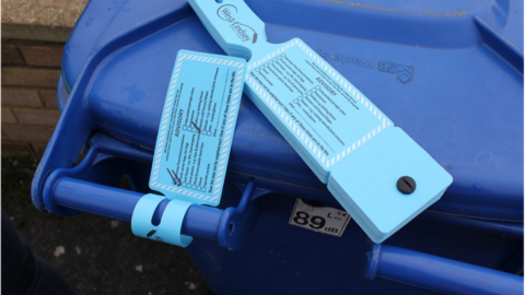 Blue bin tagged with advisory note