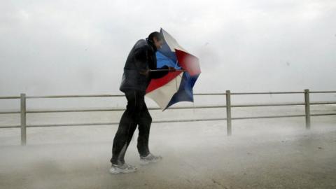 Man battles with umbrella in storm