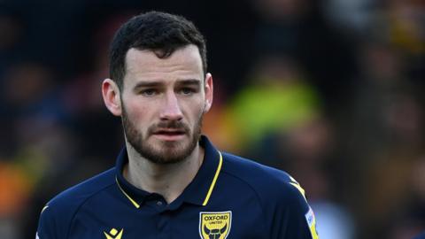 Oxford United defender Elliott Moore warming-up ahead of a League One match.