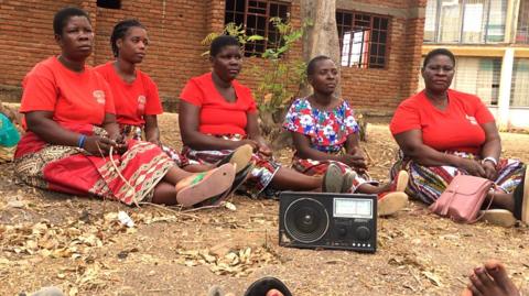Women in a village listening to a radio.
