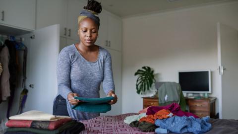 A woman folds laundry on a bed