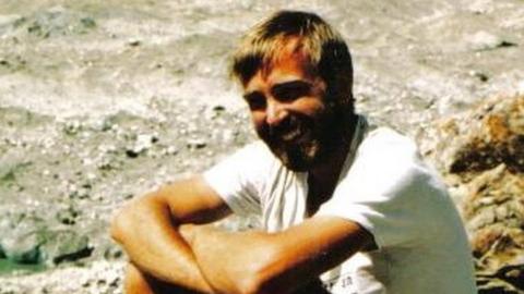 A photo of a younger Mike Thexton sitting on a rock on the Lobsang Spire mountain