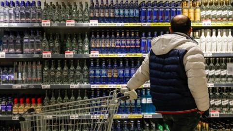 A man looks at a display of bottles of alcohol at a supermarket in Moscow.