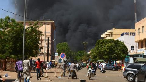 People watch as black smoke rises as the capital of Burkina Faso came under multiple attacks