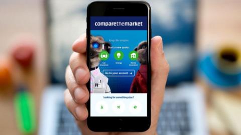 Compare The Market page on smartphone with laptop in the background