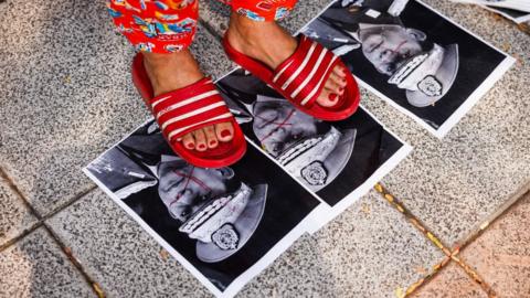 Myanmar people step on photos of military junta leader, General Min Aung Hlaing, during a gathering marking three years since the coup
