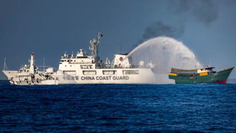 A China coast guard ship fires a water cannon at a Philippine ship in the South China Sea