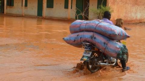 A man rides a motorbike with his belongings in a flooded street of Niamey following heavy rains, on June 15, 2017.