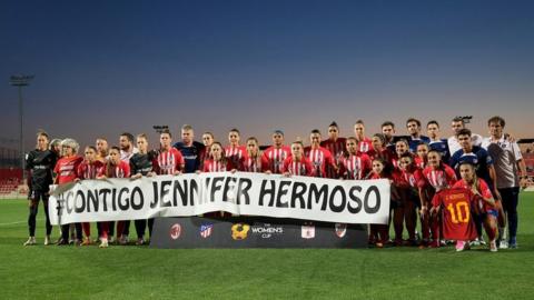 Atletico Madrid players hold a sign reading "we're with you Jennifer Hermoso" ahead of their Copa de la Reina match against AC Milan