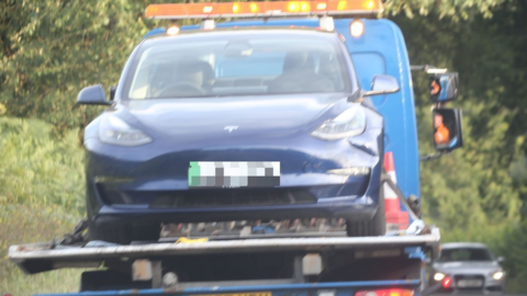 A Tesla is taken away from the crash scene