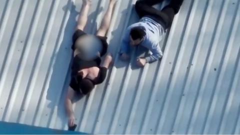 Two men on roof trying to ditch phones