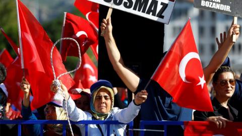 A crowd waves Turkish flags and brandishes a noose outside the court