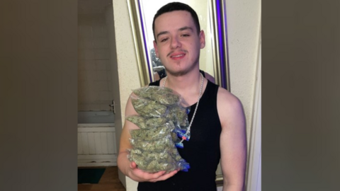 Elijah Clark holding bags of cannabis