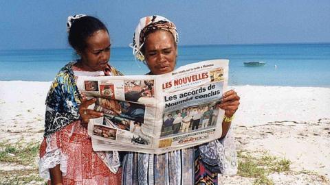 Two residents read about the historic signing of the Noumea Accord