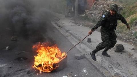 A soldier removes a burning tire settled to block a road by opposition supporters during a protest over a disputed presidential election in Tegucigalpa, Honduras December 11, 2017