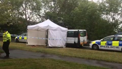 A white tent and police tape next to a taxi