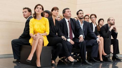 Woman in yellow sitting next to work-mates dressed in black