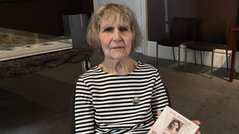 Olga holding the book about her time in captivity