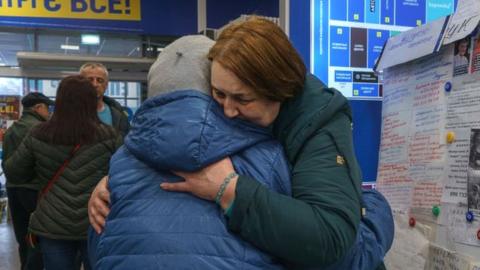 Women hug at a registration centre in Zaporizhzhia on March 29