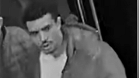 CCTV image of a man with a moustache wearing a light-coloured jacket