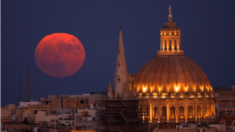 The Sturgeon Supermoon rises behind the steeple of St Paul's Anglican Pro-Cathedral and the dome of the Basilica of Our Lady of Mount Carmel in Valletta, Malta