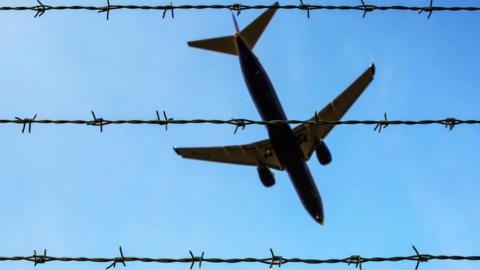 Photo of a plane taken through a barbed wire fence