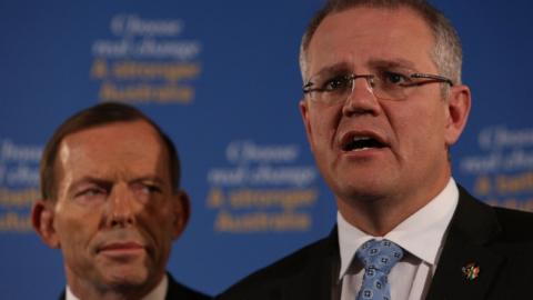 Tony Abbott watches Scott Morrison at a press conference in 2013