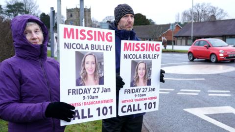 Friends of missing woman Nicola Bulley hold missing person appeal posters along the main road in the village in St Michael's on Wyre, Lancashire on 10 February 2023