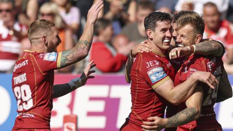 Tom Johnstone is mobbed by Catalans teammates after his hat-trick try