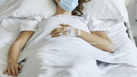 A stock image of a woman in a hospital bed