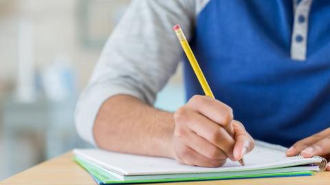 Male school student writes in a notebook