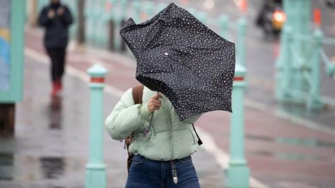 A woman walking along Brighton seafront struggles with her umbrella in the wind as Storm Francis sweeps across the south-east of England