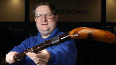 Auctioneer Karl Bennett holds a walking stick formerly belonging to Sir James Craig