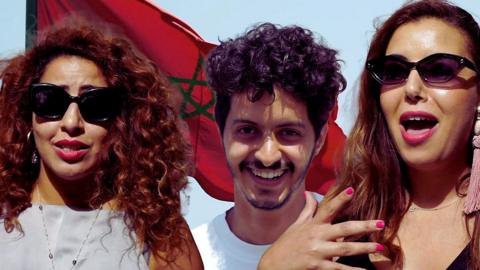 Three young Moroccans in front of the Morocco flag