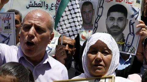 Palestinians hold posters in solidarity with Palestinians jailed in Israel at a protest in the West Bank city of Hebron (21 June 2018)