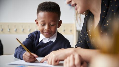 A stock image of a primary school student with his teacher