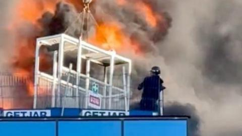 Man next to fire on roof