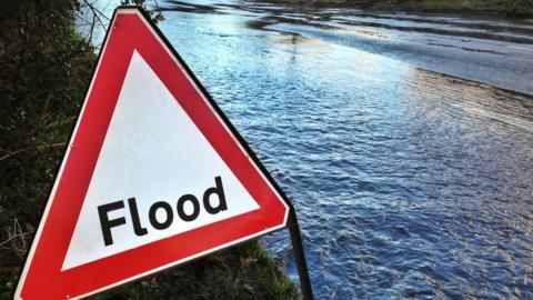 Flood sign by the side of a flooded road