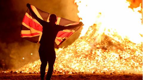 Bonfire lit with man holding union flag