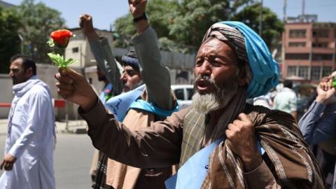 An Afghan peace protester holding a plastic rose to call for peace