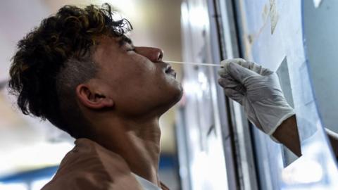 A health worker collects swab sample for COVID-19 testing at Guwahati Railway Station, in Guwahati, Assam, India on Saturday, Jan. 8, 2022.