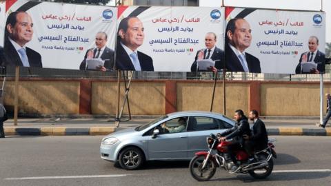 People drive past election billboards for Egyptian President Abdul Fattah al-Sisi in Cairo, Egypt (6 December 2023)