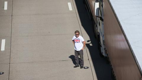 A truck driver stands next to his vehicle on the M20 during Operation Stack