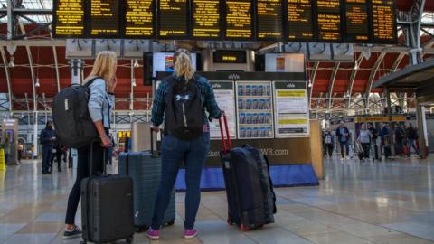 Passengers look at the information board at Paddington railway station on the third of the three days rail strike action