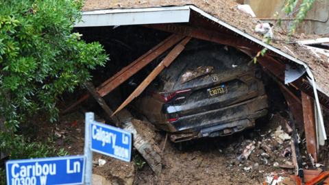 A car trapped under a collapsed building on Sunday in Southern California after a powerful storm ripped through the area
