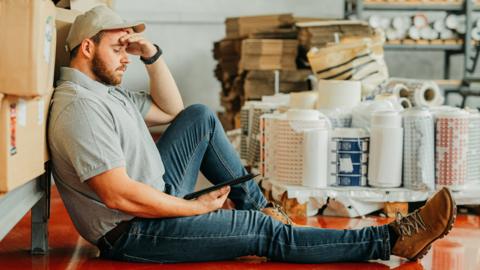 A stock photo of a tired warehouse worker